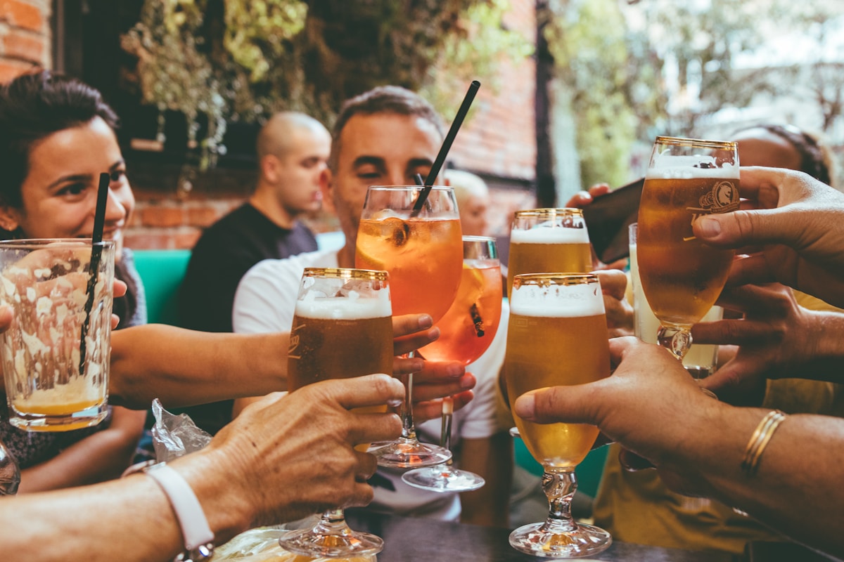 Crowd of friends socializing and toasting craft beer at lively gastro-pub